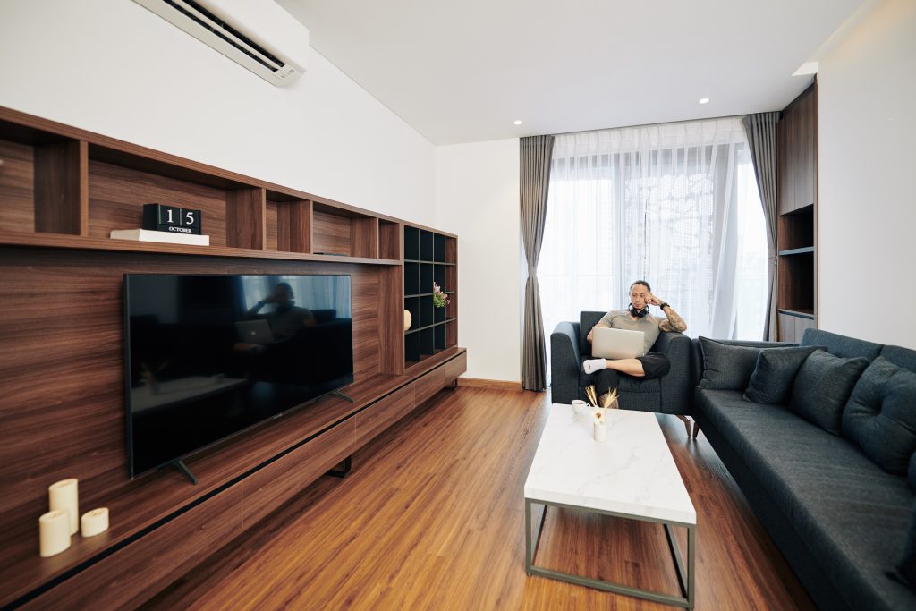 Dubai family relaxing in a bright living room with fresh airflow visuals, while technician in background closes a newly cleaned duct vent.