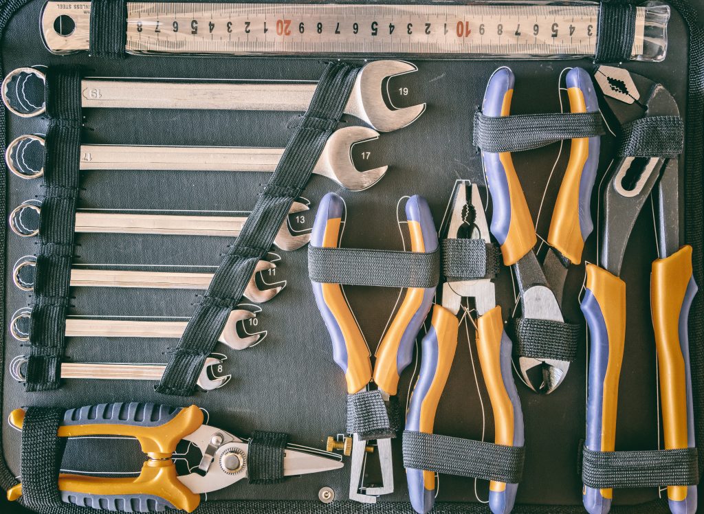 Organized set of handyman tools including drill, hammer, tape measure, screws, and paint brush on a wooden background, representing diverse home repair services in Dubai.