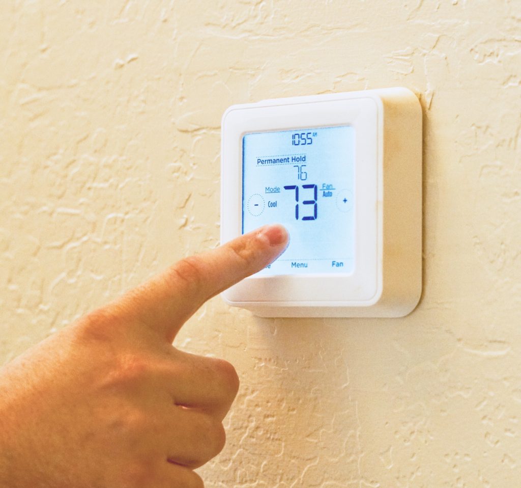 Professional AC technician adjusting smart thermostat during commercial AC servicing UAE.