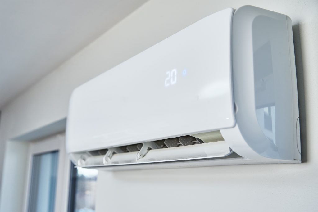 AC technician in Dubai showing a family a working AC remote with cool air blowing, symbolizing trusted servicing and improved comfort.