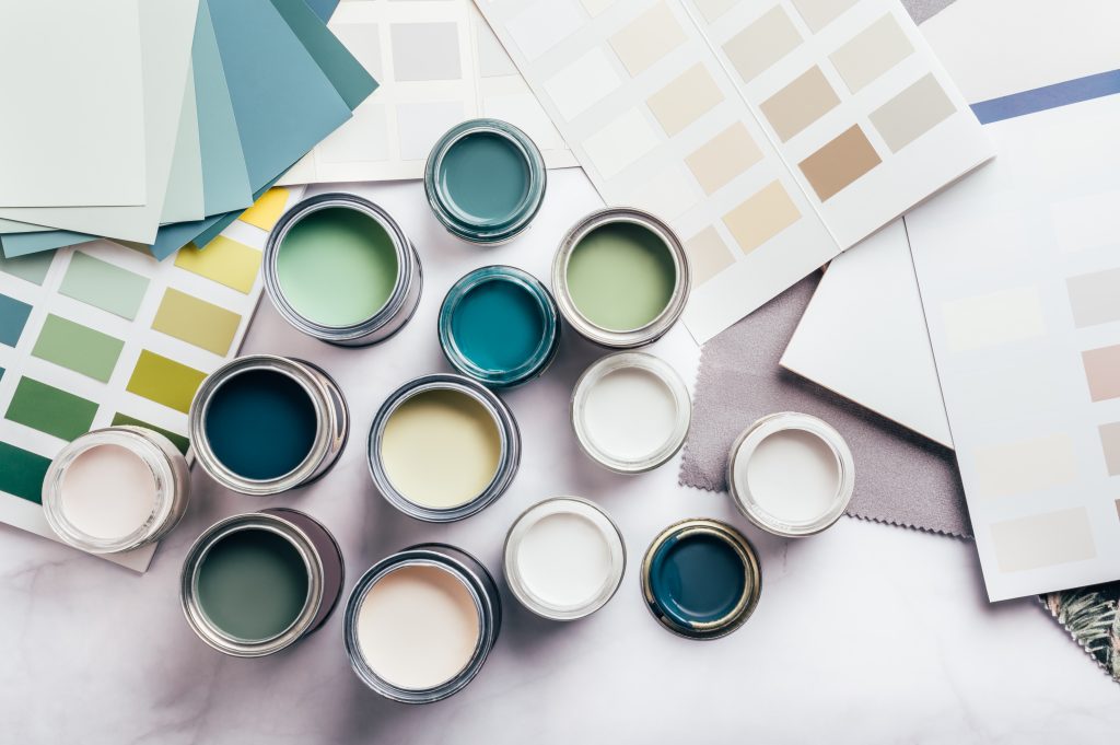 Paint cans, rollers, and color swatches neatly arranged on a workbench.
