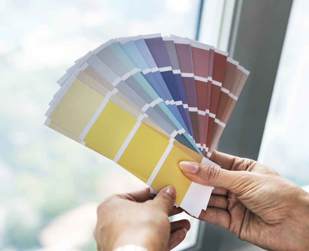 Dubai painter holding a colour palette fan deck against a freshly painted living room wall, showcasing colour matching and paint code matching.