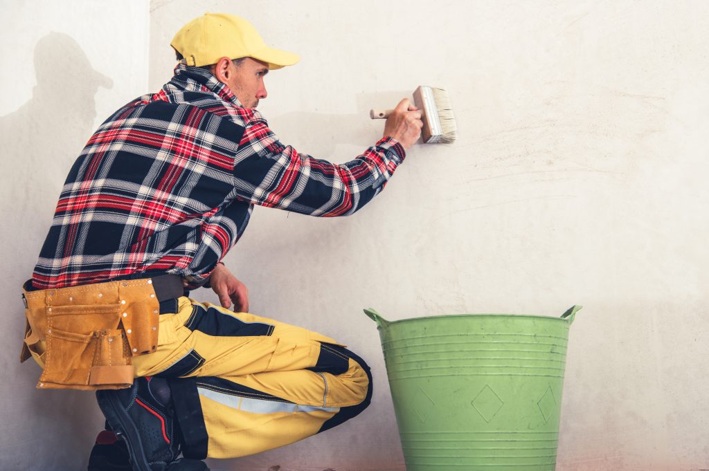 waterproofing and wall repair Sharjah painter applying sealant to outdoor wall