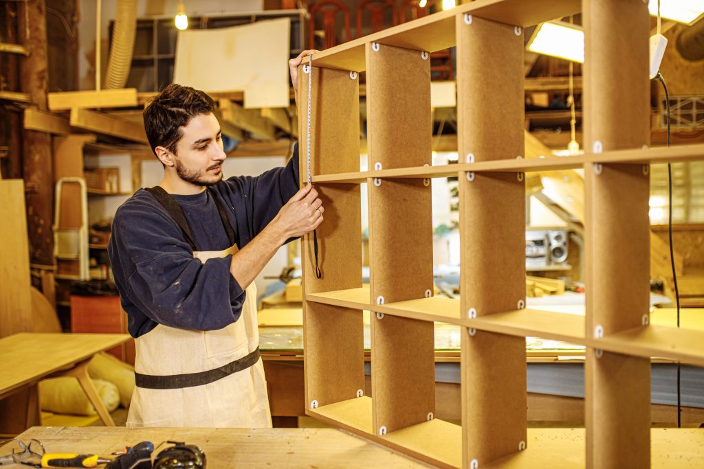 carpentry services Sharjah carpenter assembling wooden bookshelf in modern home