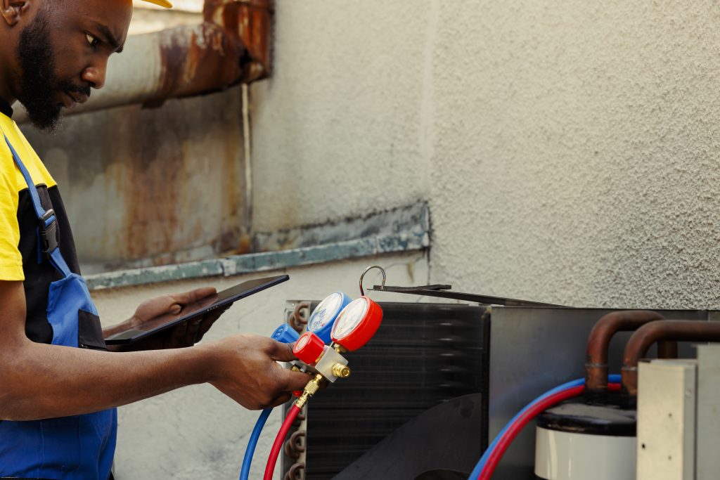 Affordable AC coil cleaning Sharjah expert holding specialized cleaning spray in front of an air conditioning unit.