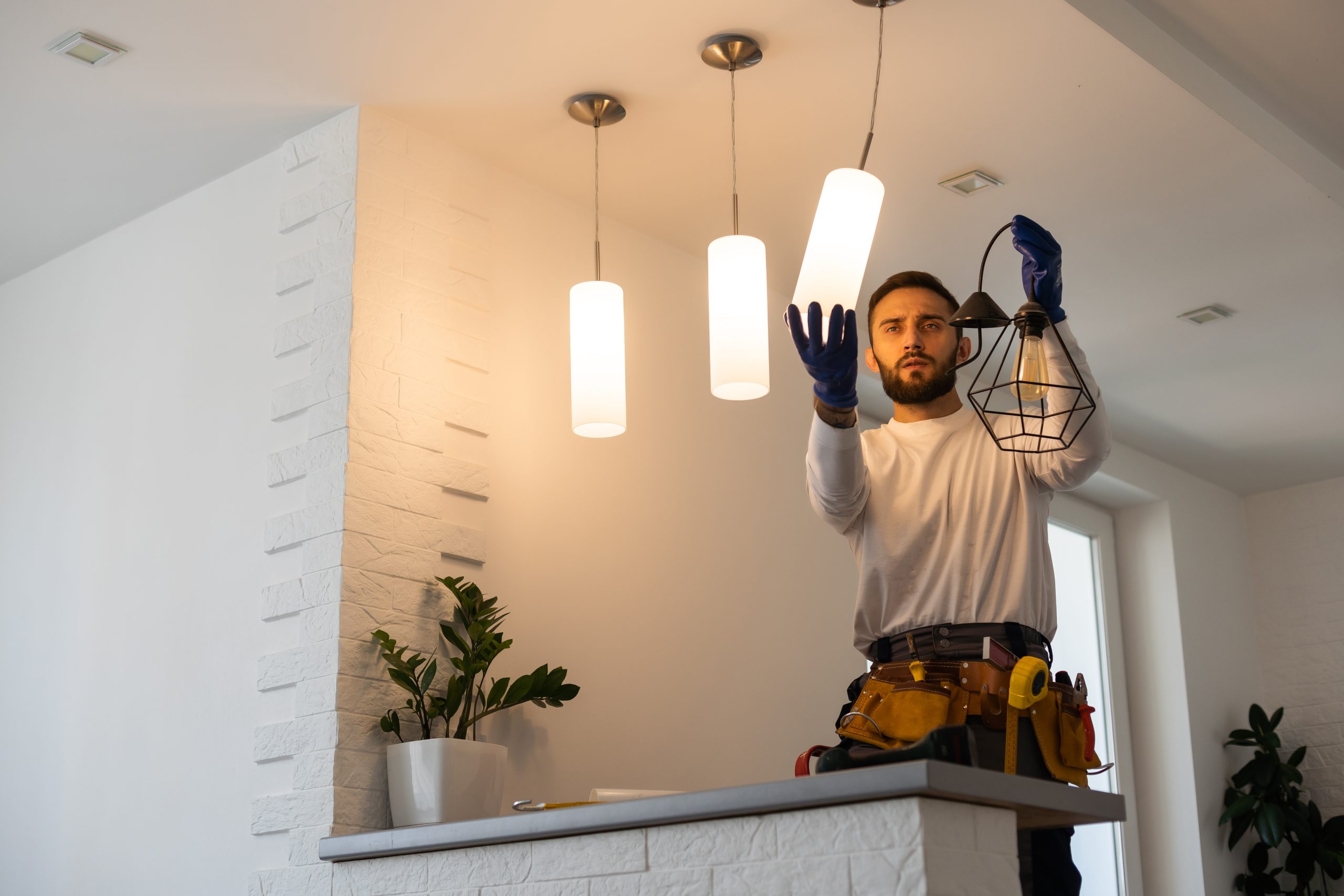 Licensed handyman UAE repairing a light fixture in a modern apartment, equipped with tools and safety gear.