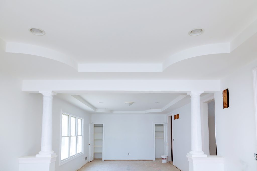 Bright villa living room in Dubai after painting, with a painter rolling up floor protection sheets to complete the post-painting clean-up.