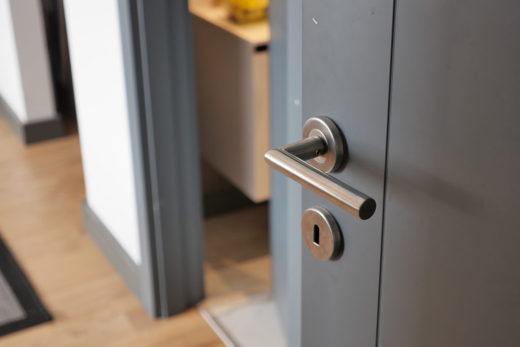 Smiling Dubai family entering their home with a newly installed lock while a uniformed locksmith departs after completing the job.