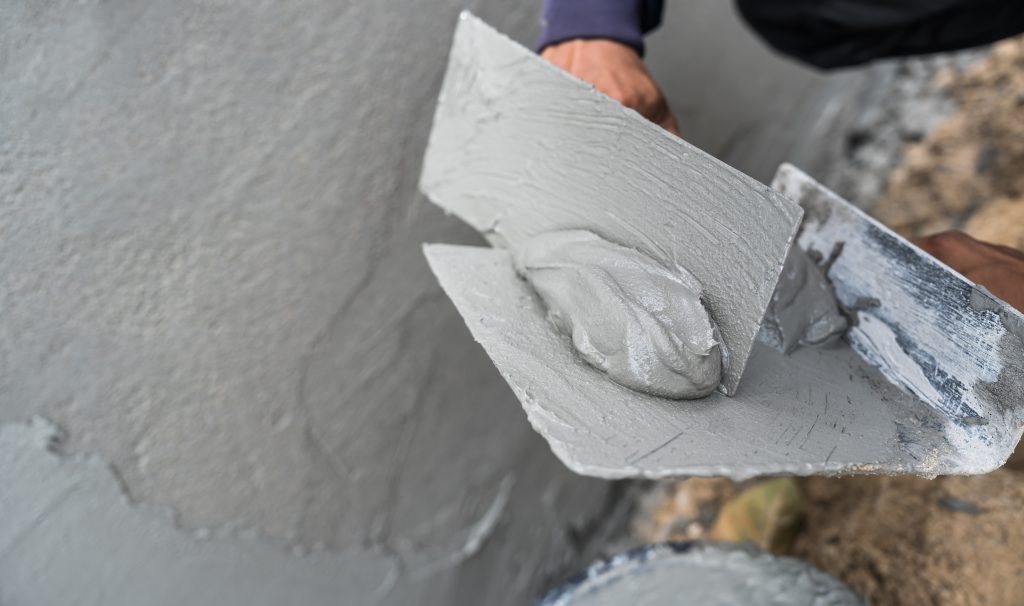 Applying plaster to a wall with a metal trowel in Dubai.