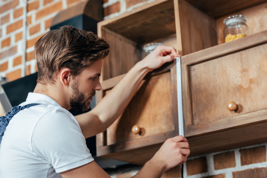 Professional carpenter in Dubai assembling a wooden cabinet in a modern living room, with tools neatly arranged for precise craftsmanship.