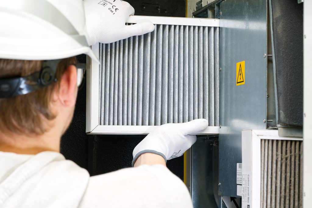 Same-day AC maintenance UAE technician replacing AC filter in home.