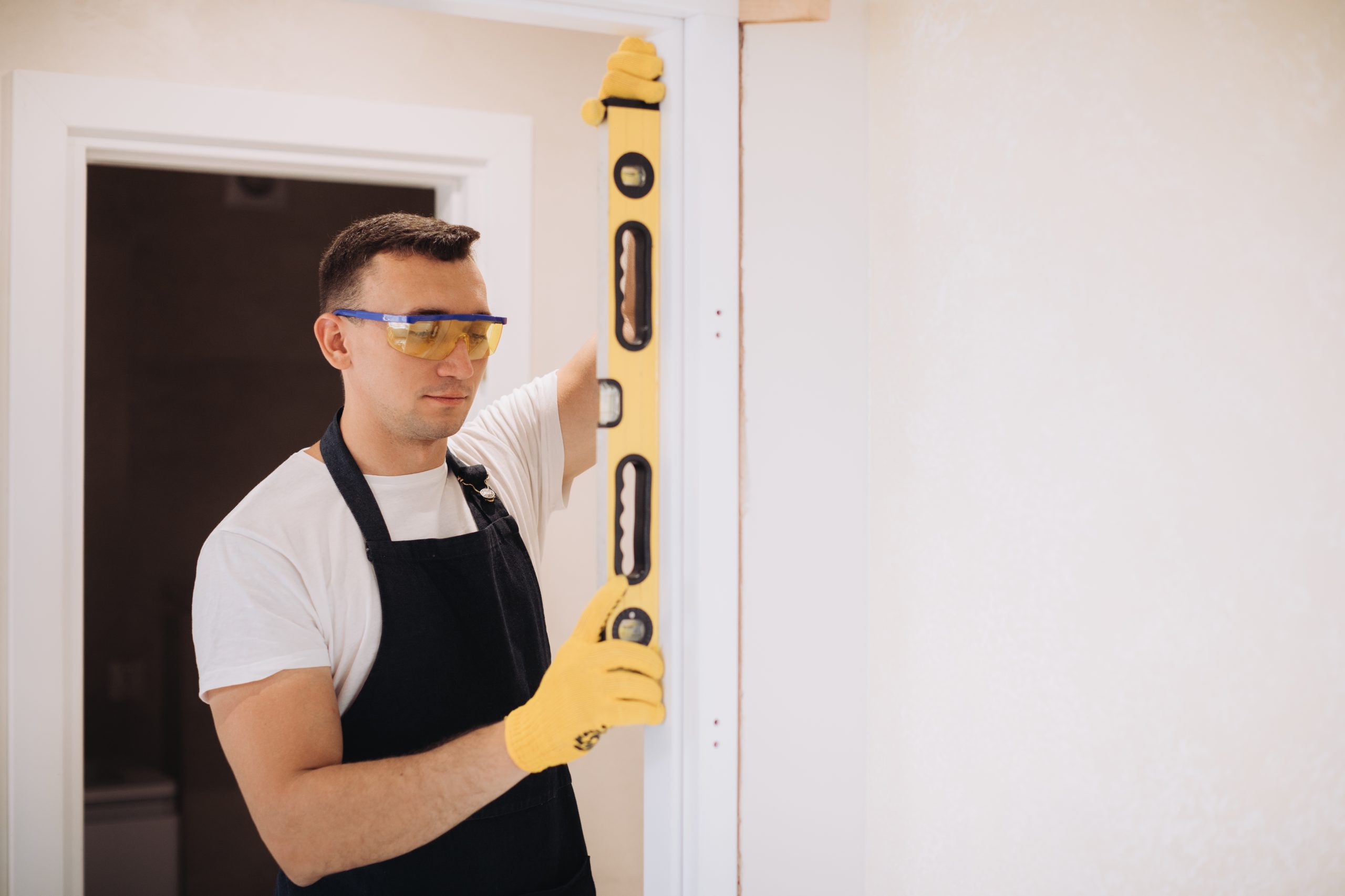 Professional handyman in Sharjah repairing a wooden door frame with precision tools.