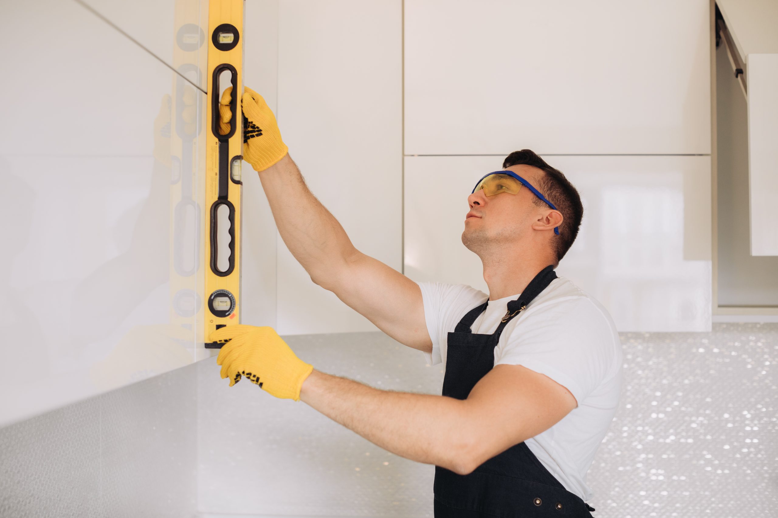 Professional handyman in Abu Dhabi installing a wall shelf with gloves and precision tools, delivering reliable home repair services.