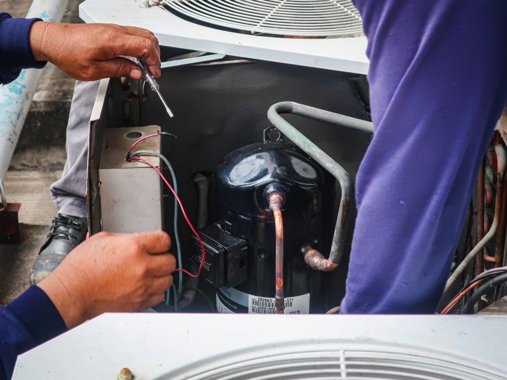 Technician in Abu Dhabi showing customer a clean and dirty AC coil comparison after licensed HVAC coil cleaning service.
