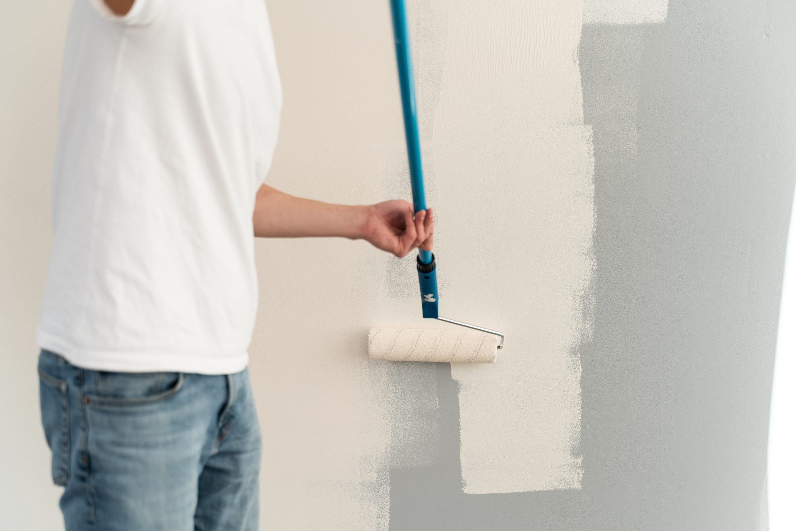 Painter adding finishing touches to wall paint in Dubai interior.