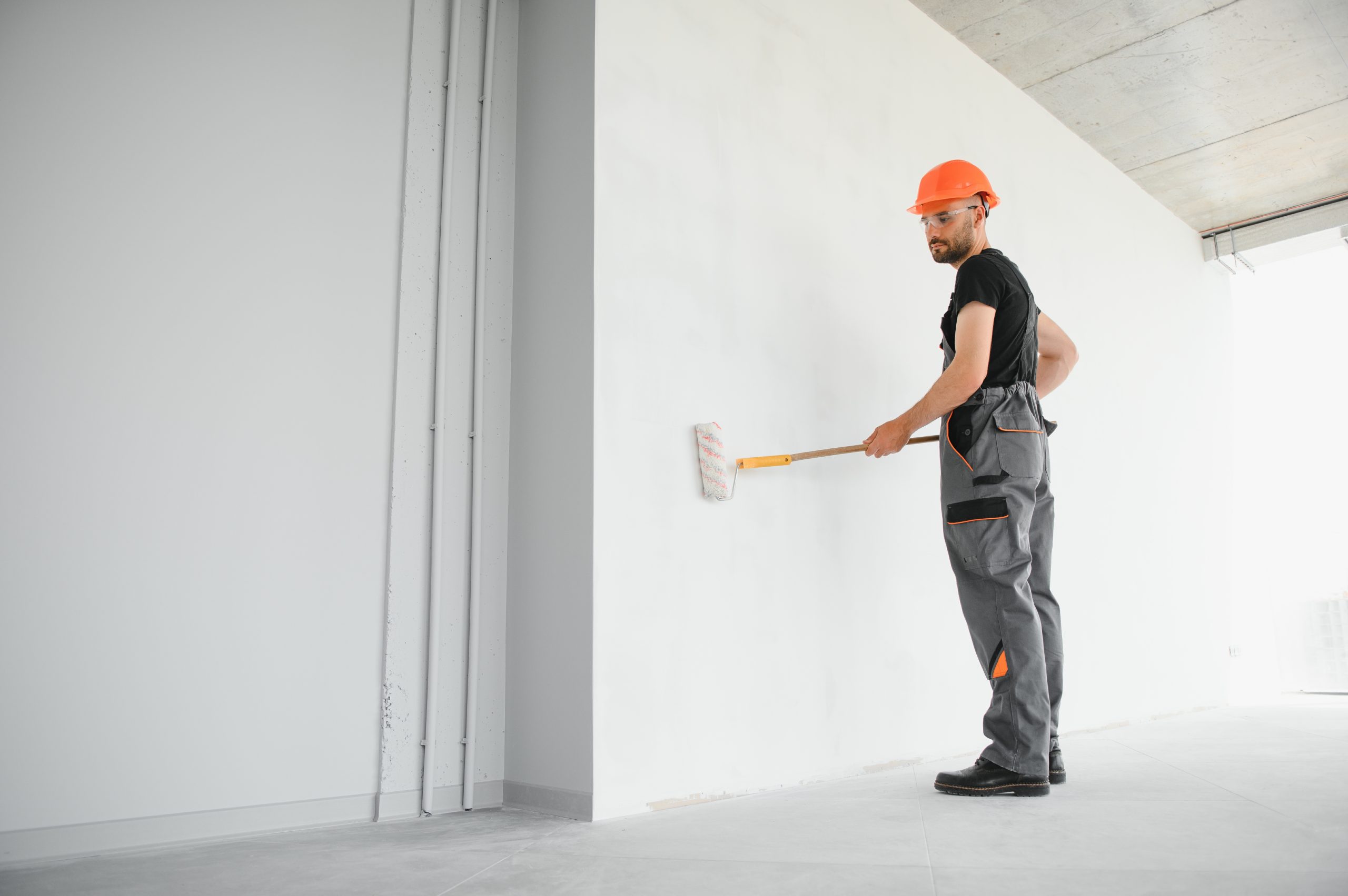 Painter preparing wall edges with masking tape before painting in Dubai.