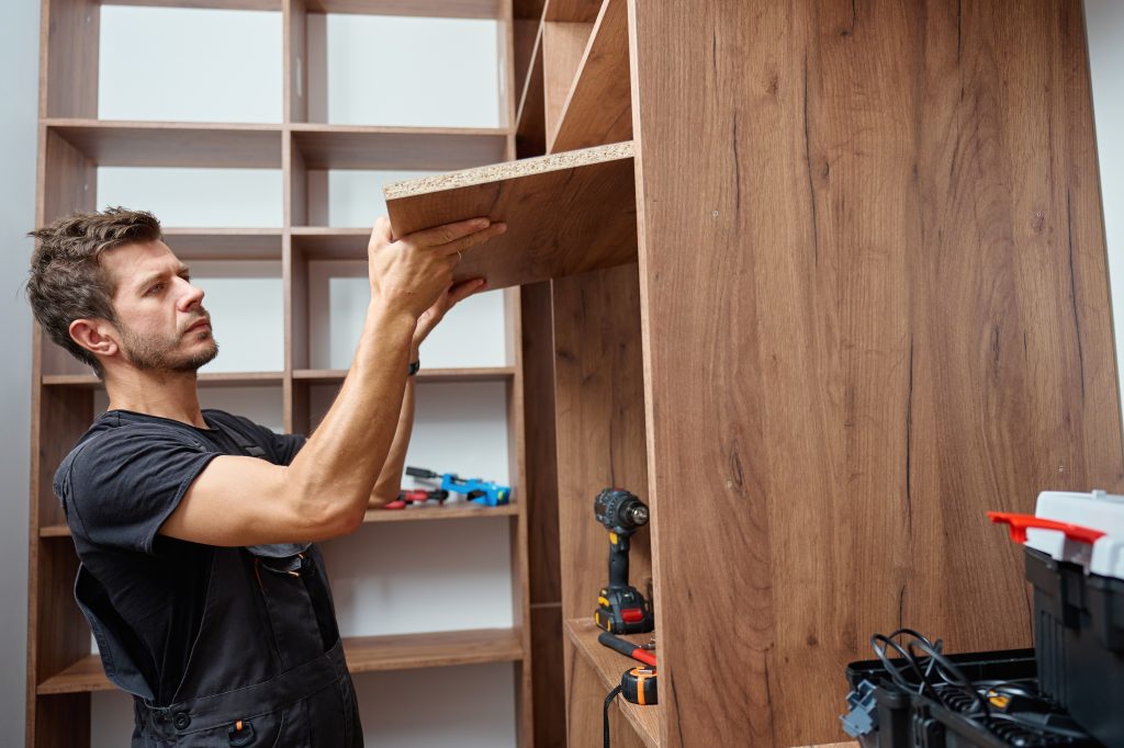Dubai carpenters in uniforms installing cabinets in an apartment while the homeowner supervises, reflecting quality and trust.