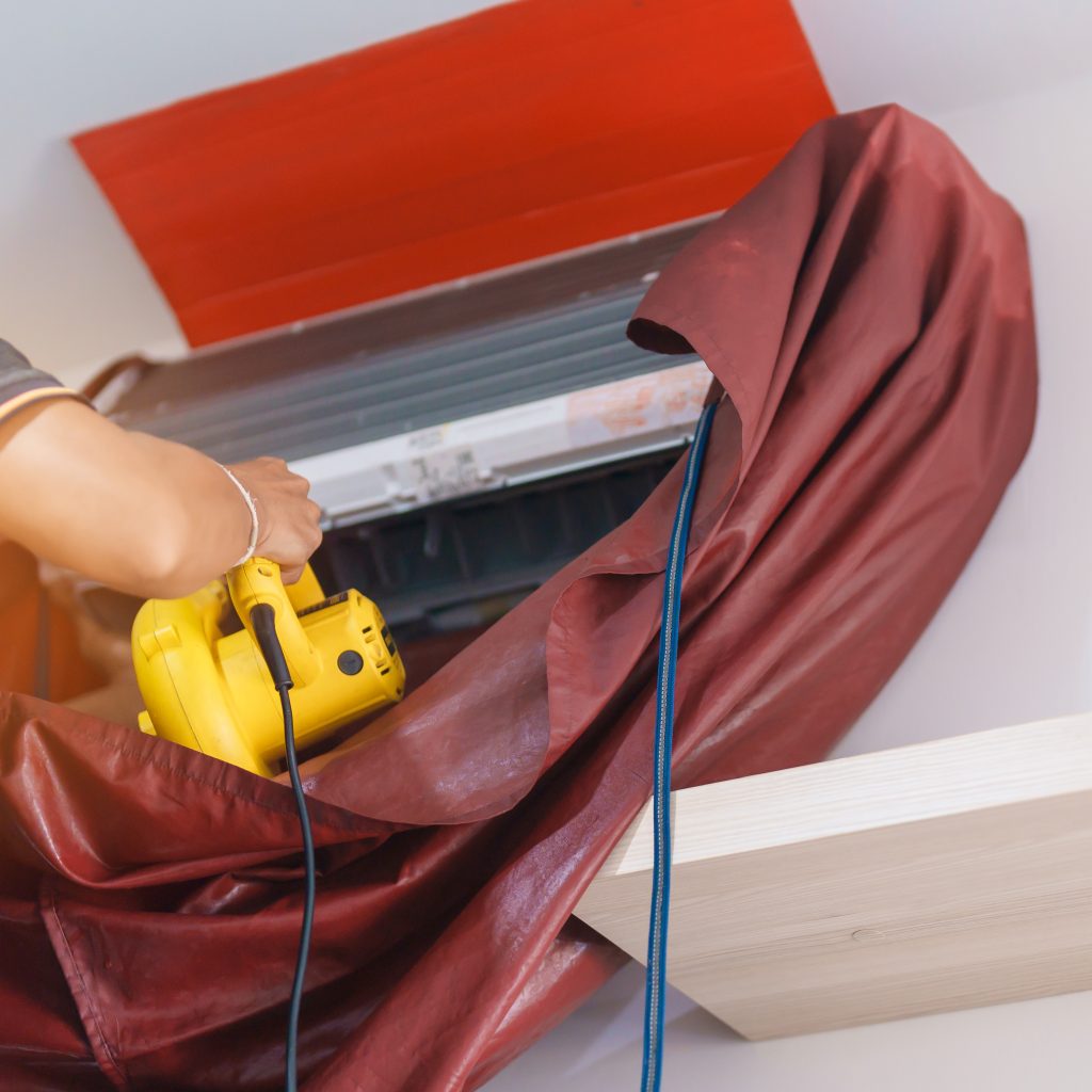 AC maintenance near me Sharjah - Licensed technician using industrial equipment for coil cleaning.