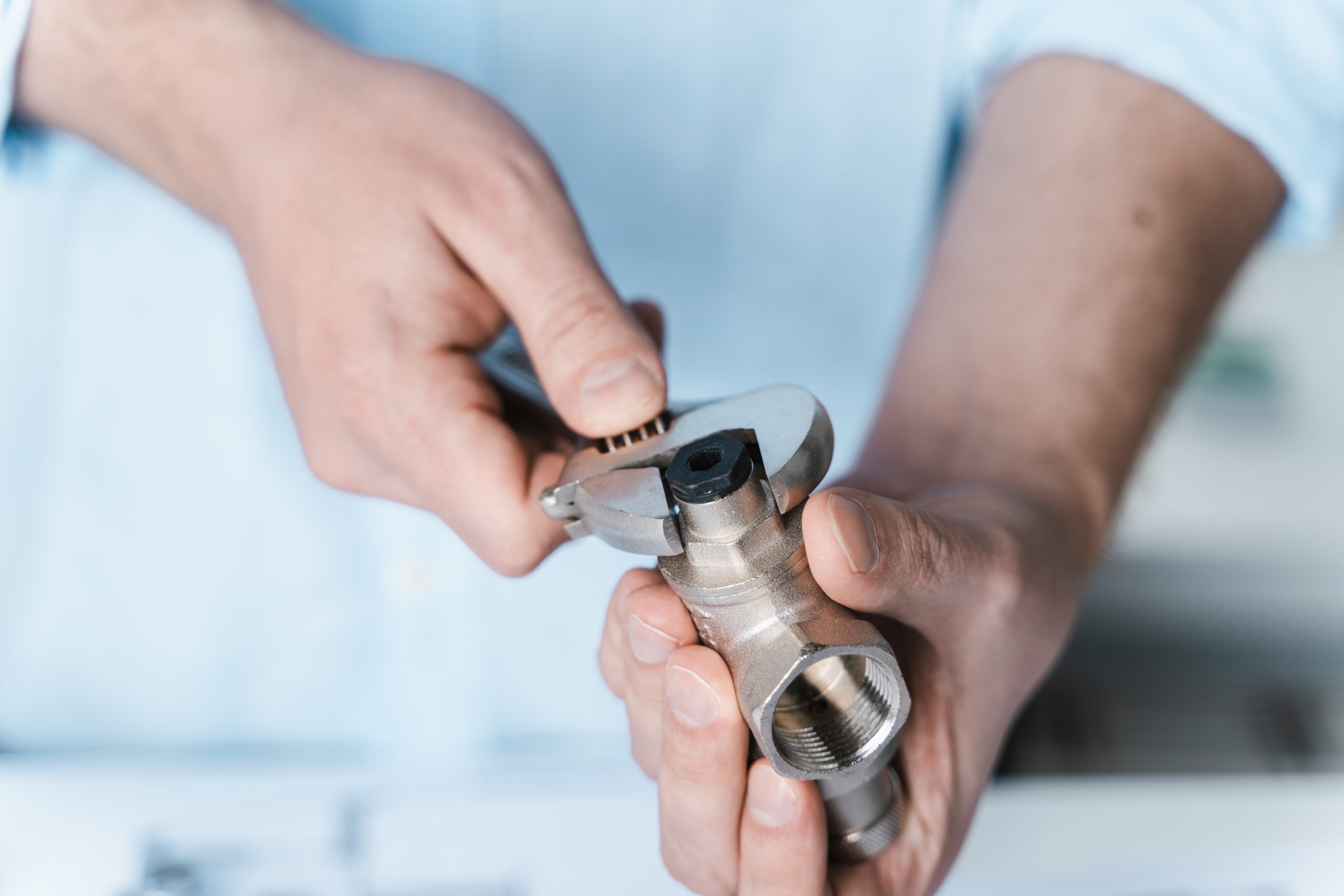 Pipe repairing Dubai - plumber tightening kitchen sink pipe joint.