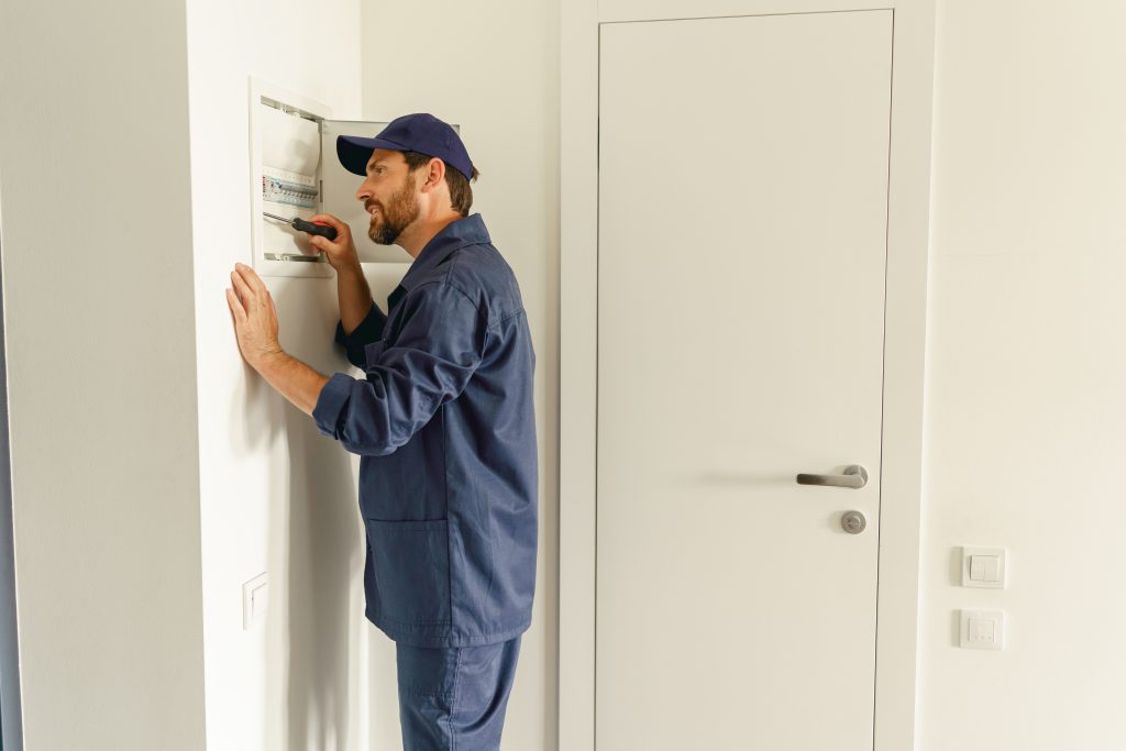 Air conditioner maintenance Ajman near me - Licensed technician cleaning coils and inspecting wiring in apartment.