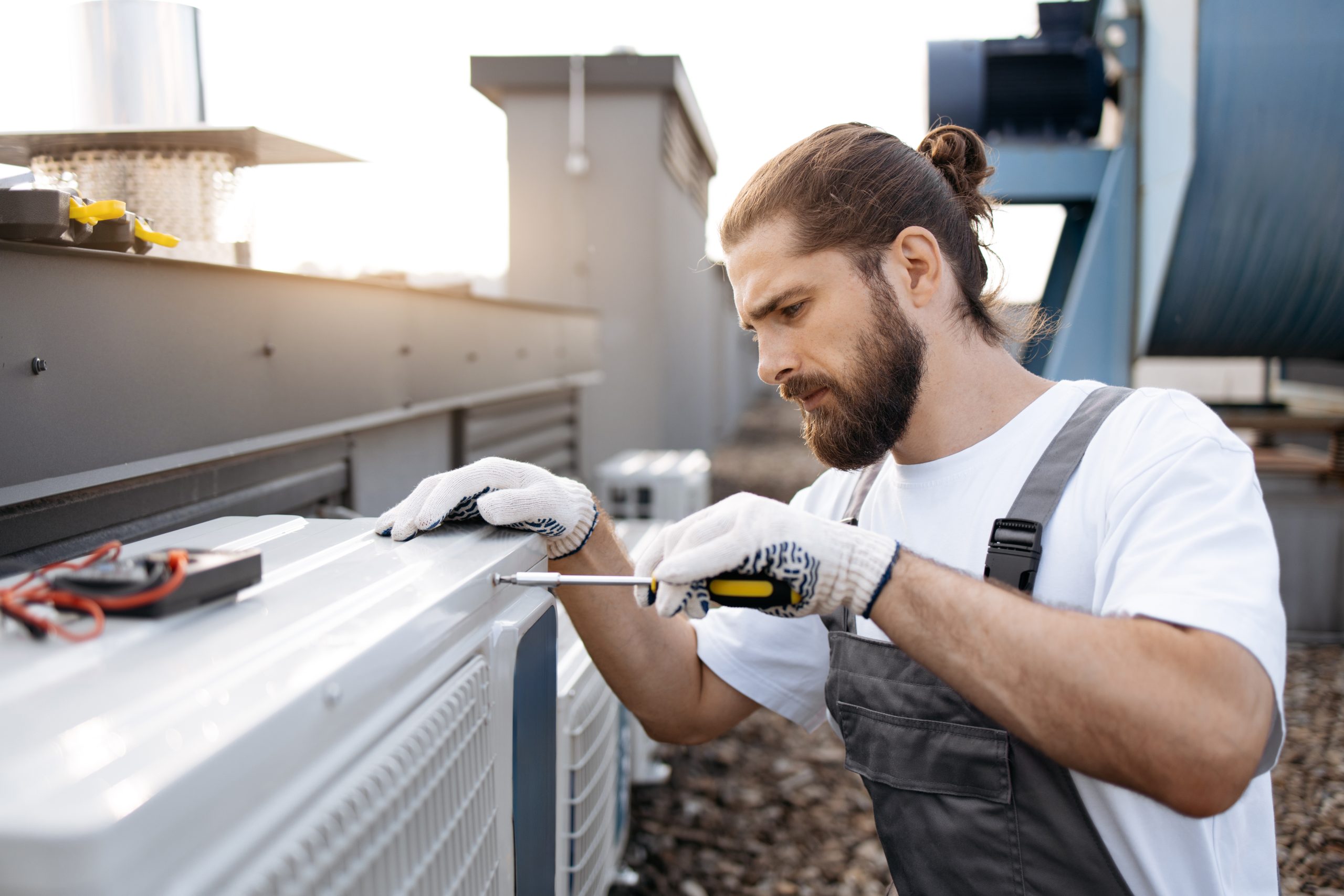 Technician cleaning outdoor AC condenser coil in UAE villa with professional equipment.
