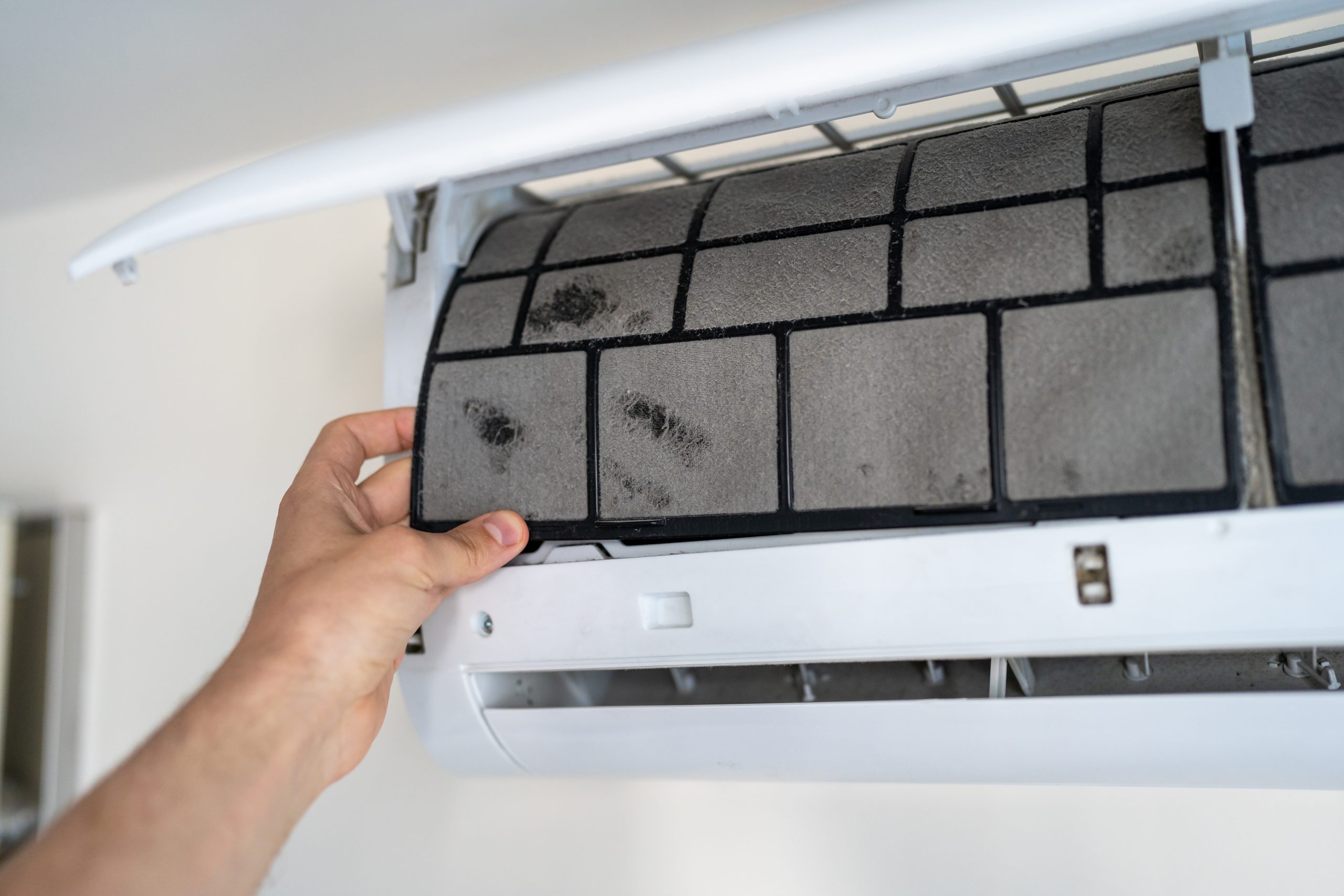 Customer using mobile phone to book AC coil cleaning services Ajman with Ajman location pin visible.