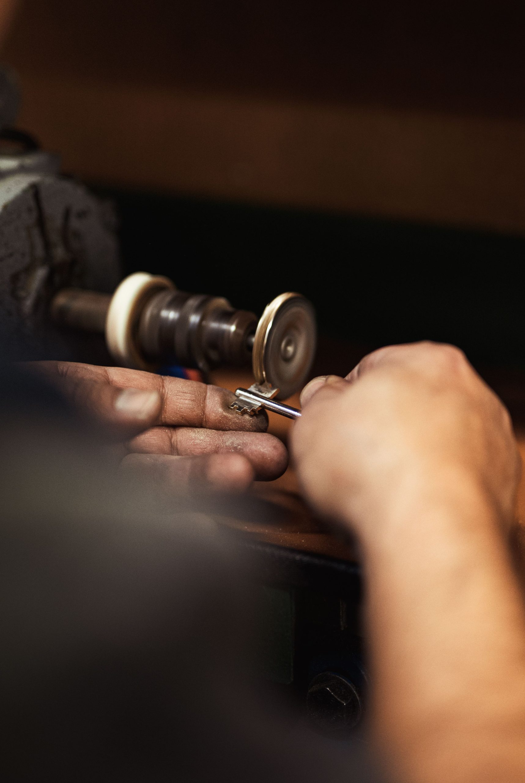 Locksmith in Dubai cutting a new key on a professional machine while explaining the process to the client.