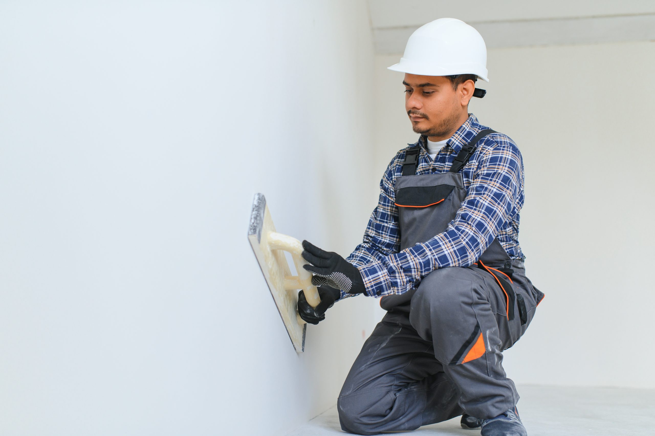 Worker applying weatherproof plaster to an exterior villa wall.