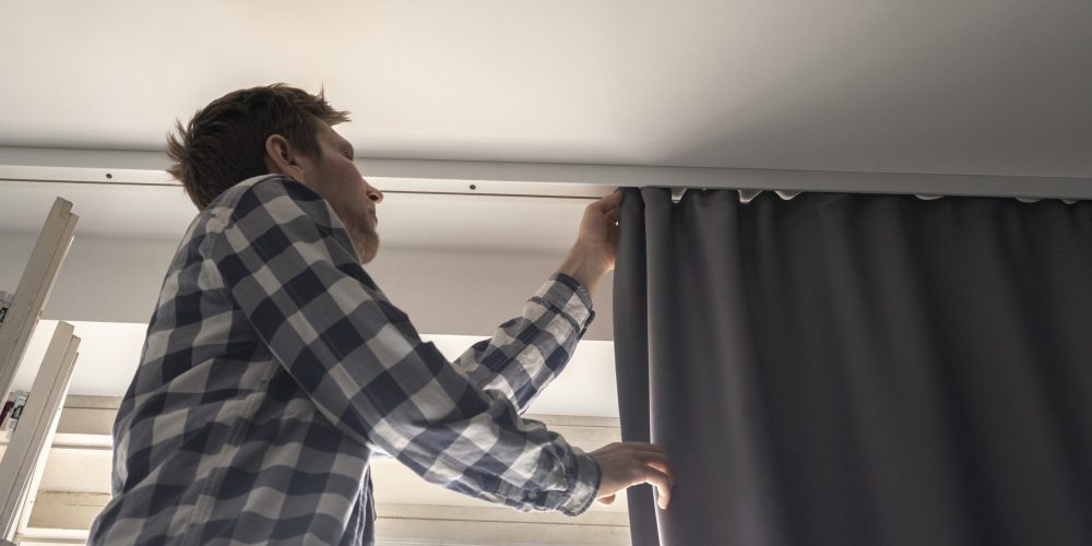 Professional handyman in Dubai mounting a curtain rod in a bright living room, with tools organized and homeowner smiling in approval.