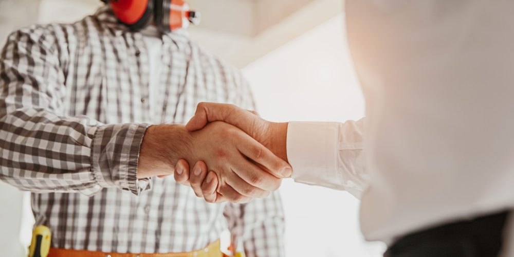 Licensed handyman in Abu Dhabi shaking hands with a happy homeowner in a stylish apartment, symbolizing trust and professionalism.