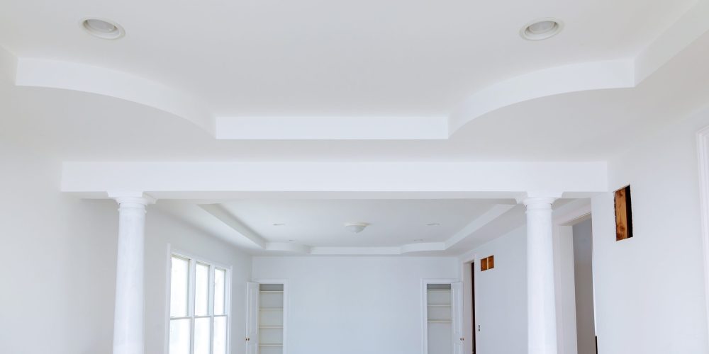 Bright villa living room in Dubai after painting, with a painter rolling up floor protection sheets to complete the post-painting clean-up.