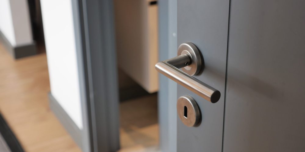 Smiling Dubai family entering their home with a newly installed lock while a uniformed locksmith departs after completing the job.