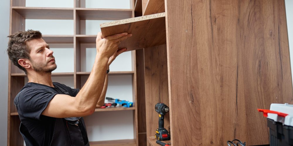 Dubai carpenters in uniforms installing cabinets in an apartment while the homeowner supervises, reflecting quality and trust.