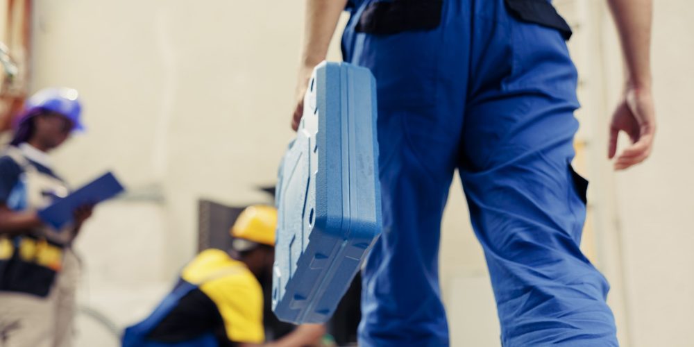Two Dubai plumbers carrying equipment into a villa with a branded service van parked outside, ready for residential plumbing services.
