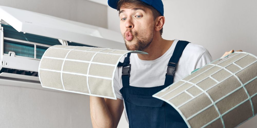Professional AC servicing Ajman - Smiling technician showing clean filters to satisfied family.