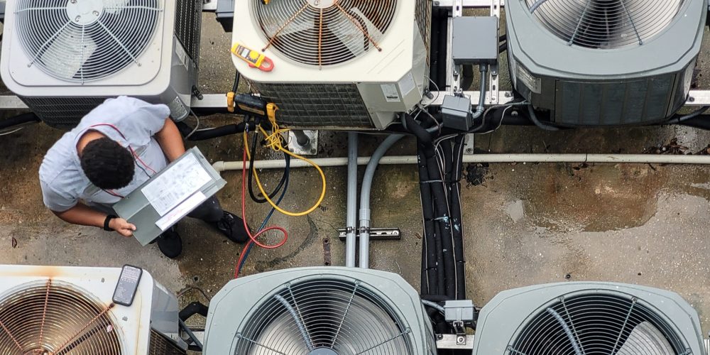 Licensed AC servicing Abu Dhabi team servicing multiple AC units in high-rise building.
